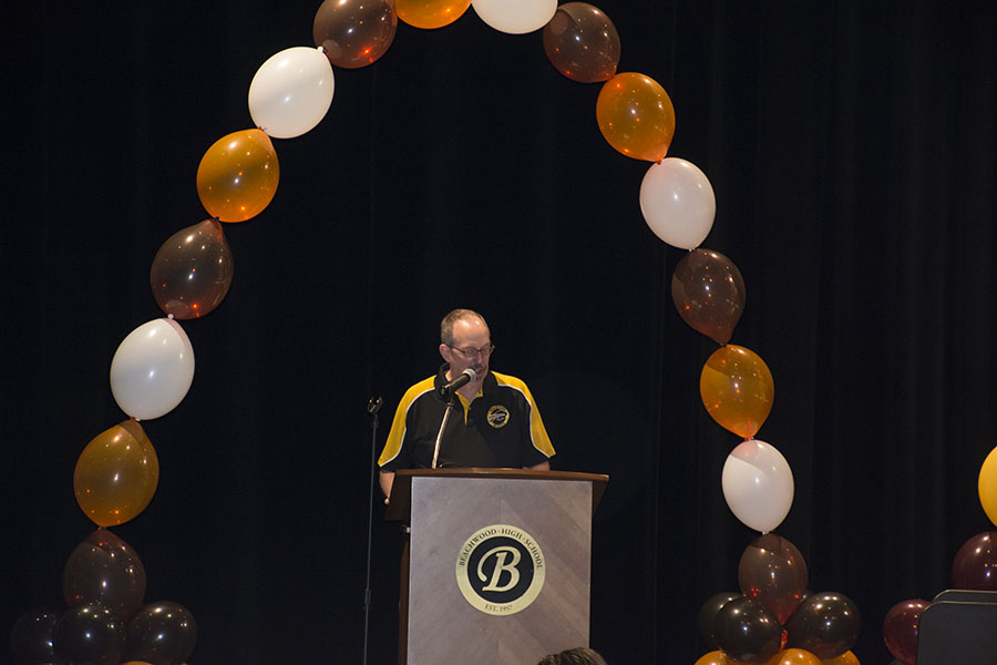 Interpreter Mark Howdieshell announces Top 12 candidates at an assembly in 2017