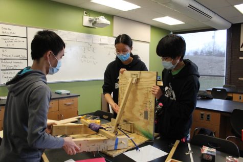 Seniors Christian Wu and Evelyn Zhang with junior Kai Zheng disassemble their construction for the trajectory event in order to make adjustments.