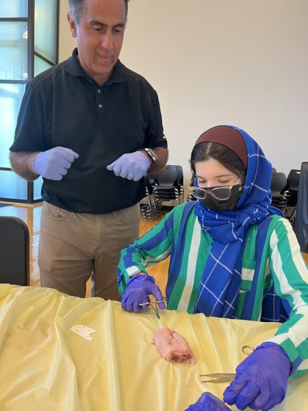 Dr. Tony Daher, an emergency medicine physician at Ahuja Medical Center, teaches Anah Khan how to complete sutures on pigs feet during a pre-med meeting last year.