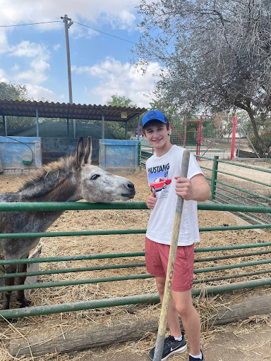 Taking a break from raking hay to pet the donkey at Kibbutz Magen.
